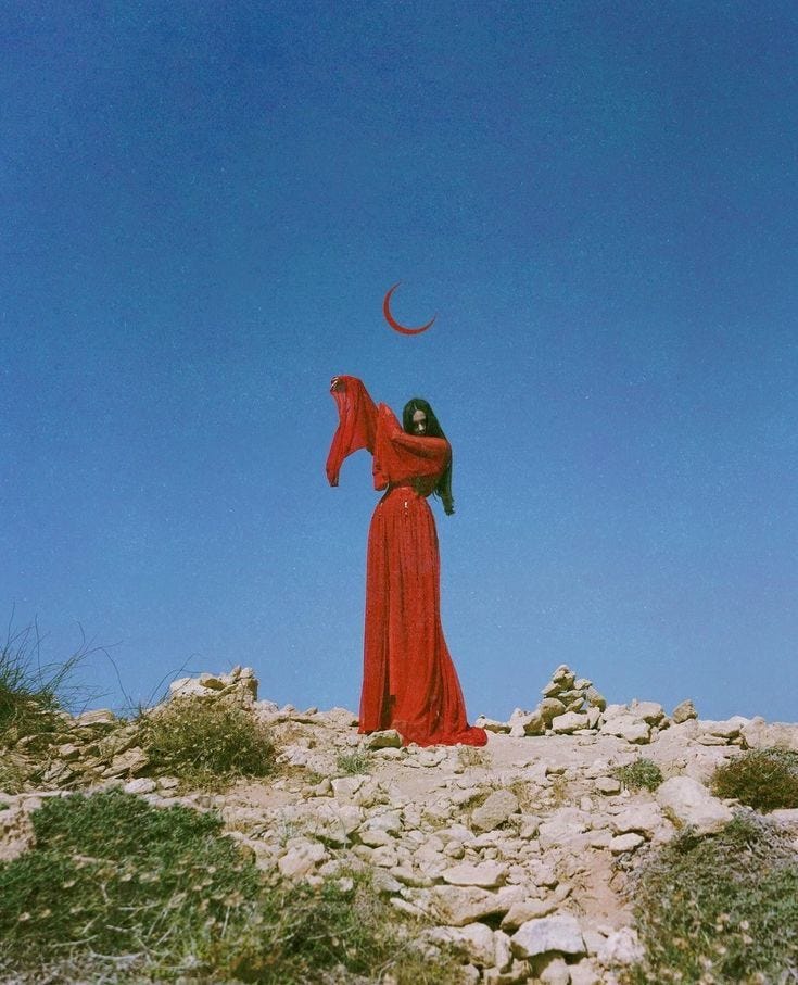 This may contain: a woman in a long red dress standing on top of a rocky hill with a crescent above her head