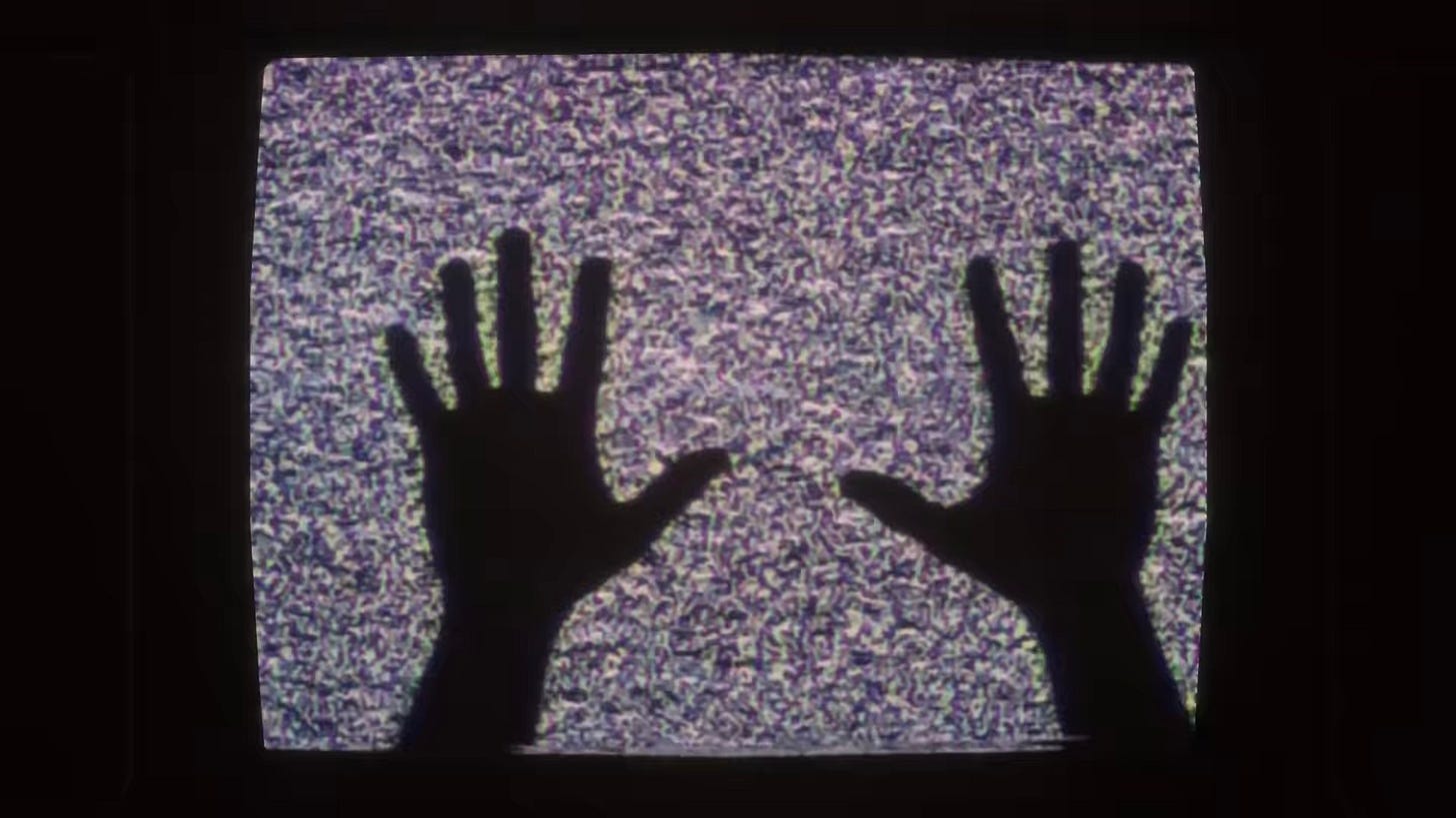 The silhouette of Jordan's hands up against a static TV screen from ATA 3.