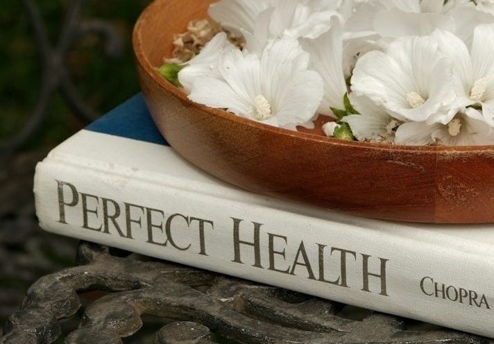 Bowl of white flowers atop a book