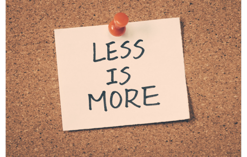 Corkboard with pinned note that says "less is more".