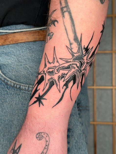 9 photos of tattoos i did this month. from top left to bottom right: a stuffed animal from item label called a peepy, a spiky chain link, a dog dragon, a starry sacred heart, a little guy holding a leaf, another chainlink with a dark black spiky background, another chain link, a brick with leaves growing out of it, and a spiral star on someones elbow (ouch!)