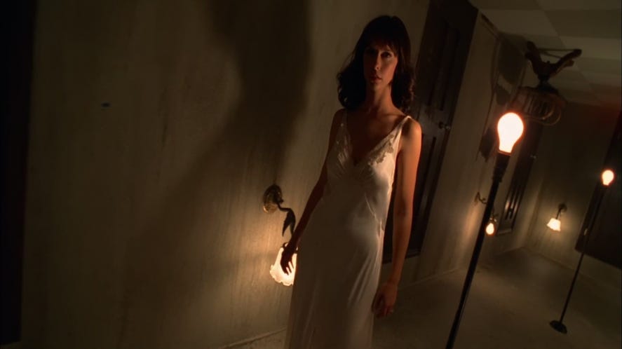 Jennifer Love Hewitt as Melinda Gordon walls down an upside down hallway in a silky bias cut ivory nightgown with lace neckline detail