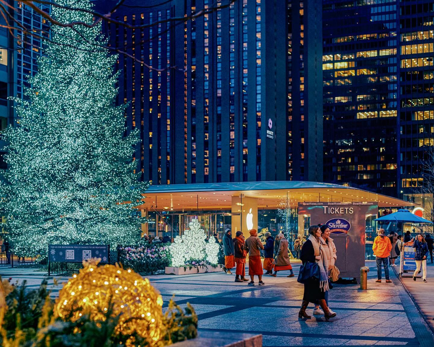 Apple Michigan Avenue at night, pictured from the plaza, which is adorned with a Christmas tree and holiday decorations.