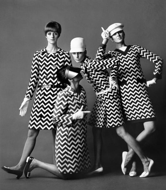 Photo en noir et blanc de 4 jeunes femmes en robes à motif géométrique et couvre-chefs pops.