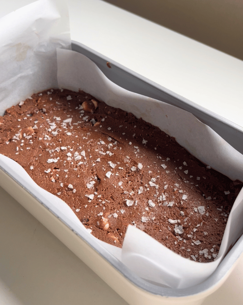 protein fudge in a grey loaf pan with coarse sea salt on top