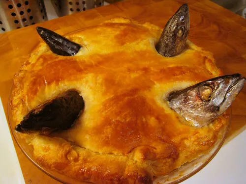 A baked stargazy pie with fish heads and tails sticking up out of the pie crust A baked stargazy pie with fish heads and tails sticking up out of the pie crust