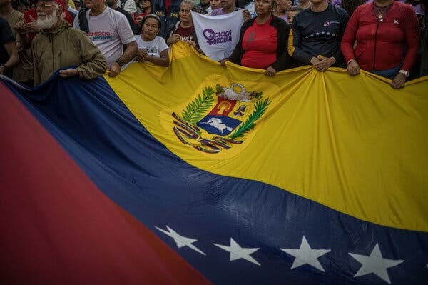 Una fila de personas sostiene una gran bandera venezolana. Una fila de personas sostiene una gran bandera venezolana.
