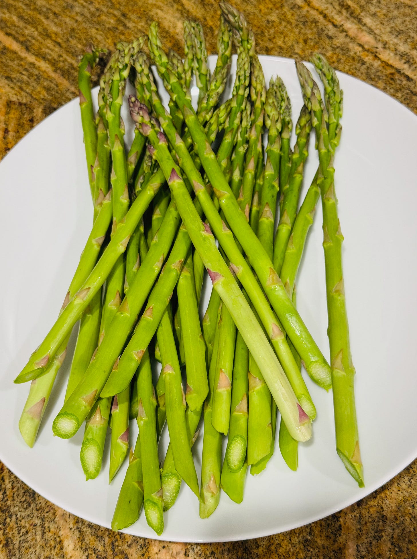 Fresh spring asparagus on a white plate — the seasonal side dish in Doug's Easter pork tenderloin recipe at The Dinner Bell Hearth