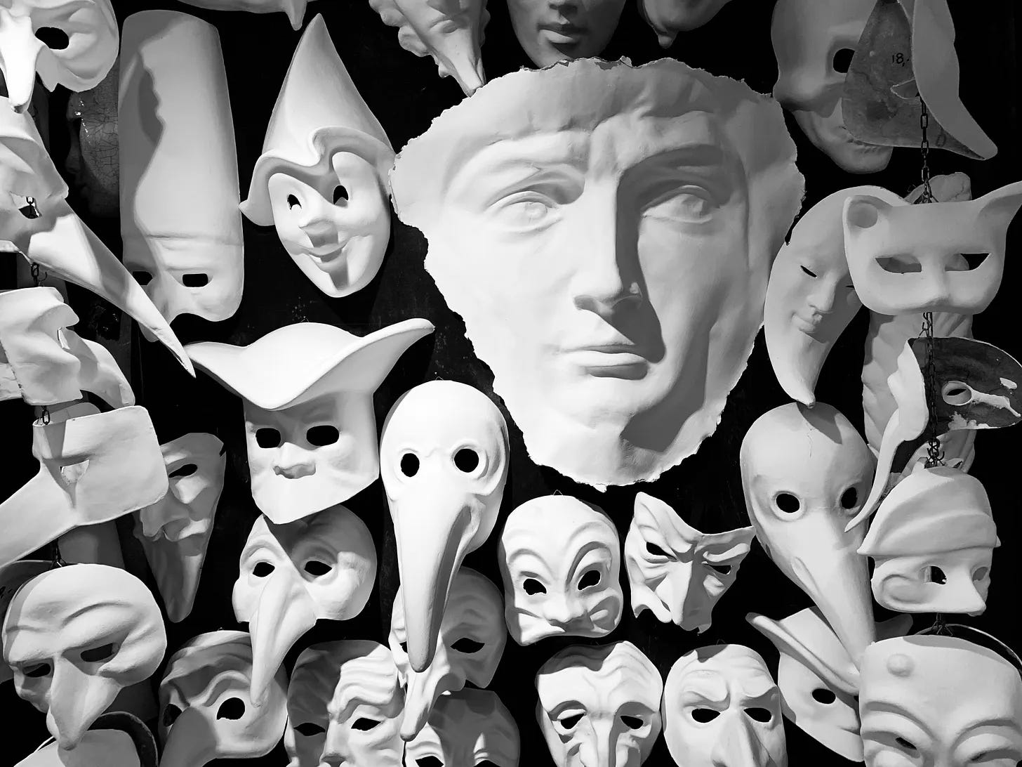 Black-and-white photograph of a large collection of theatrical masks surrounding a classical sculpted face at the centre.