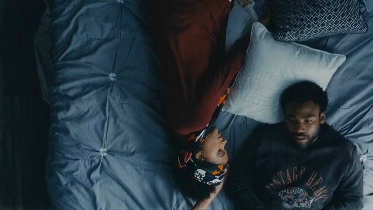 This may contain: a man and woman laying in bed together