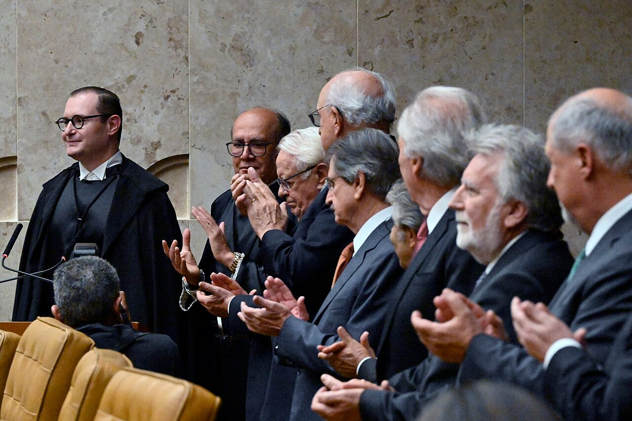 Zanin stands in a black judicial robe at the left as Lula and other officials applaud inside the Supreme Court.