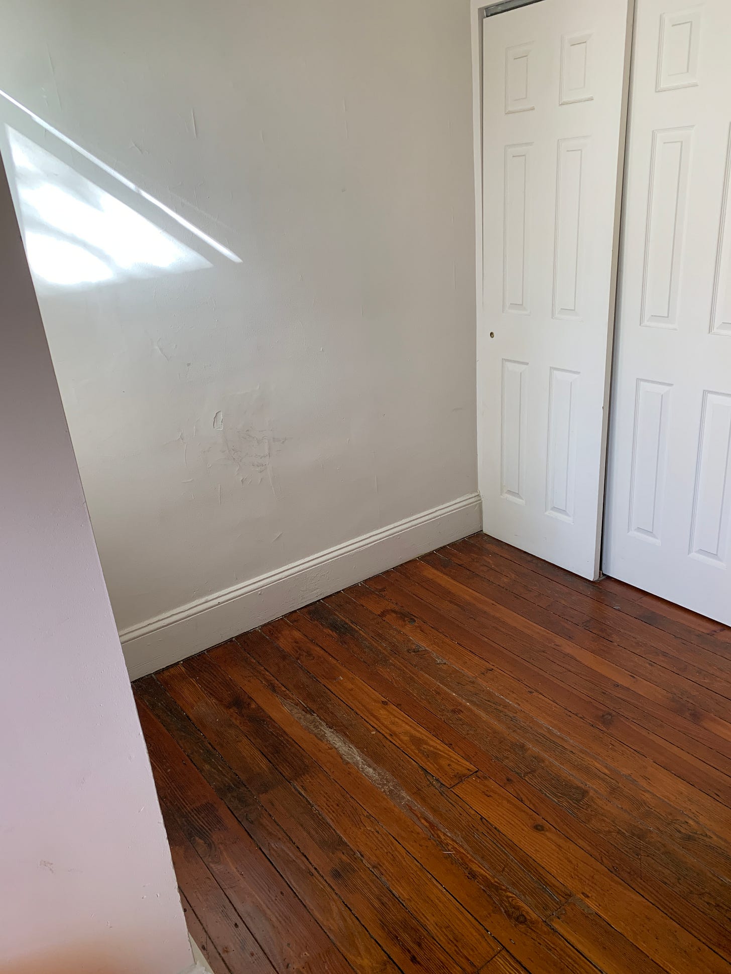 a photograph of an empty room, with hardwood floors and white walls