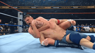 two men are wrestling in a wrestling ring with a main event banner behind them two men are wrestling in a wrestling ring with a main event banner behind them