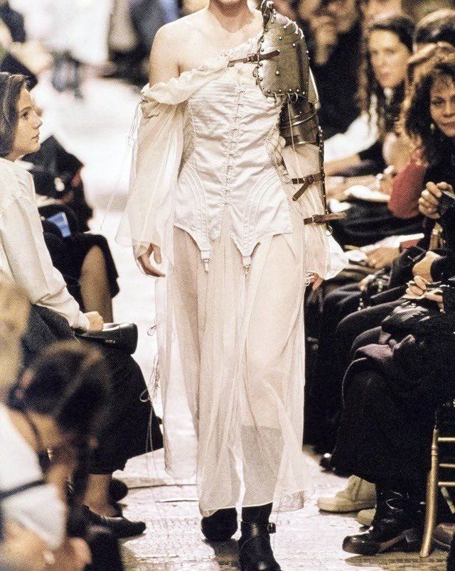 This may contain: a woman walking down a runway with lots of people in the background