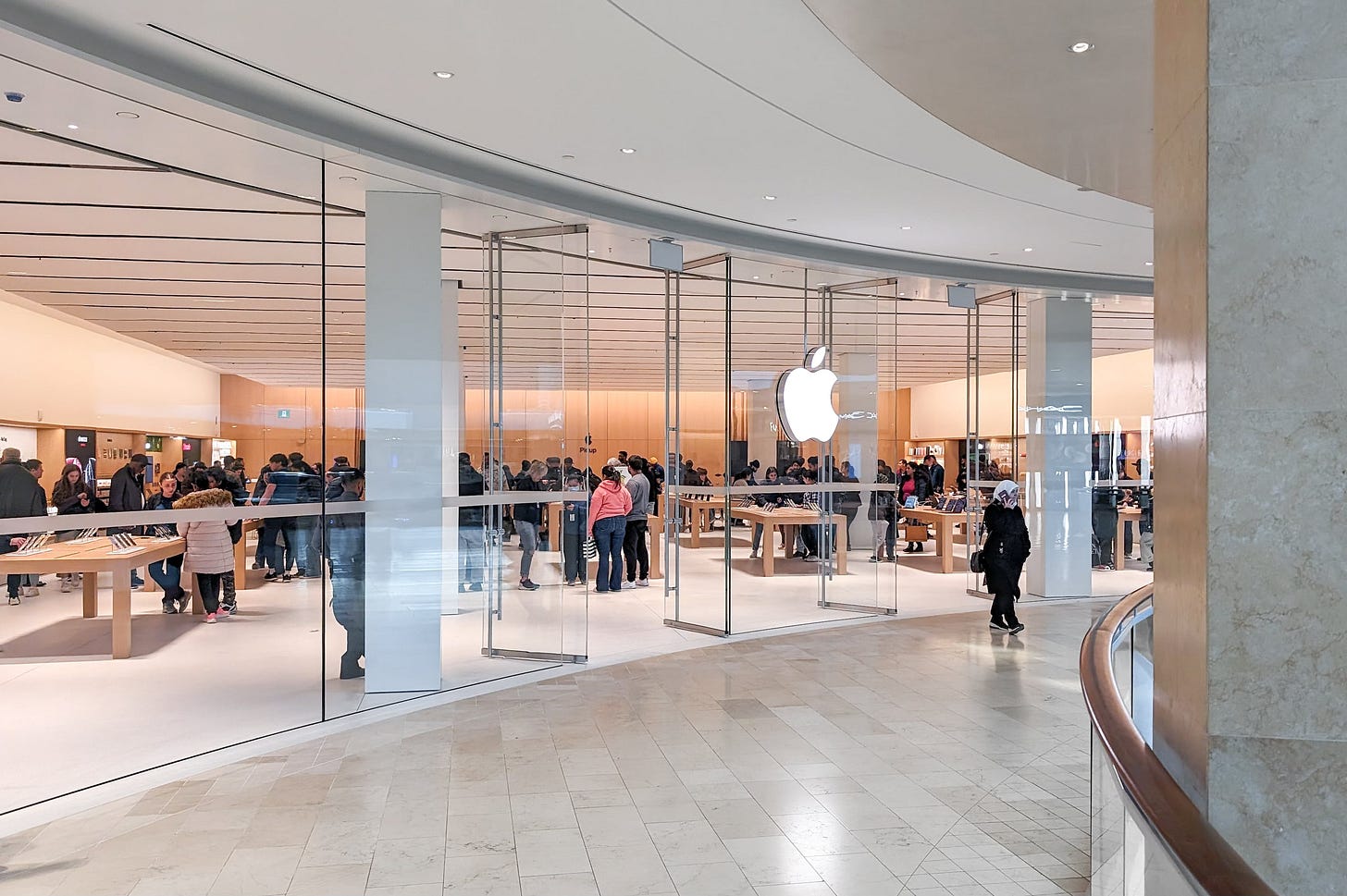 The exterior of Apple Square One, viewed from the mall corridor. This perspective shows the sweep of the curved glass and wood back wall. The exterior of Apple Square One, viewed from the mall corridor. This perspective shows the sweep of the curved glass and wood back wall.
