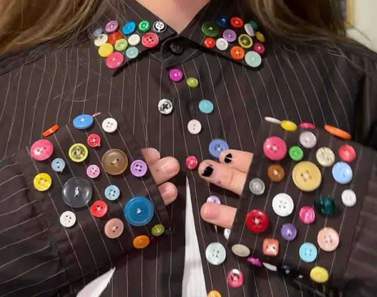 This may contain: a woman with buttons on her jacket is holding out her hands and showing the button holes This may contain: a woman with buttons on her jacket is holding out her hands and showing the button holes