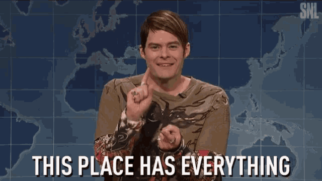 a man is pointing at the camera with the words " this place has everything " behind him