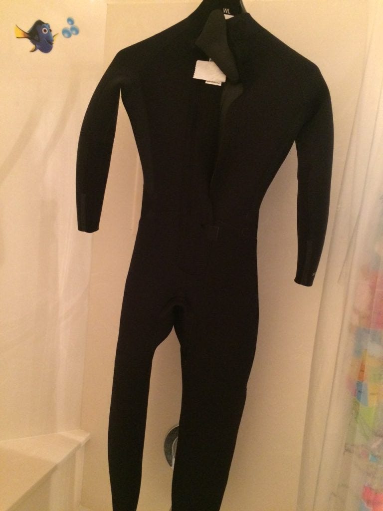 Black, long sleeve triathlon wetsuit hanging up on door