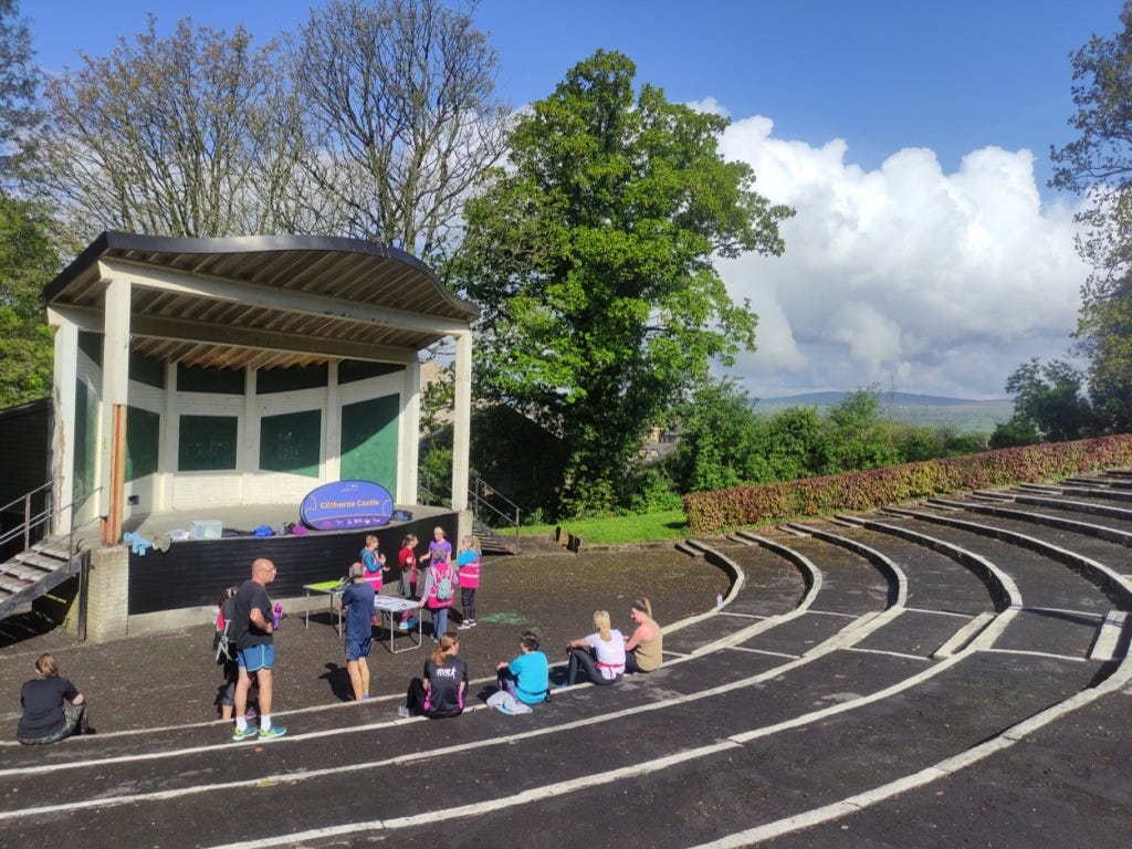Tiered concrete steps provide seating in front of the bandstand, on which sits the Clitheroe Castle parkrun sign.