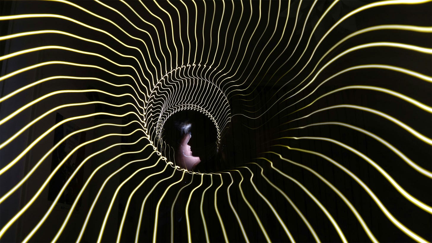 A dark spiral leads to the silhouette of a human face.