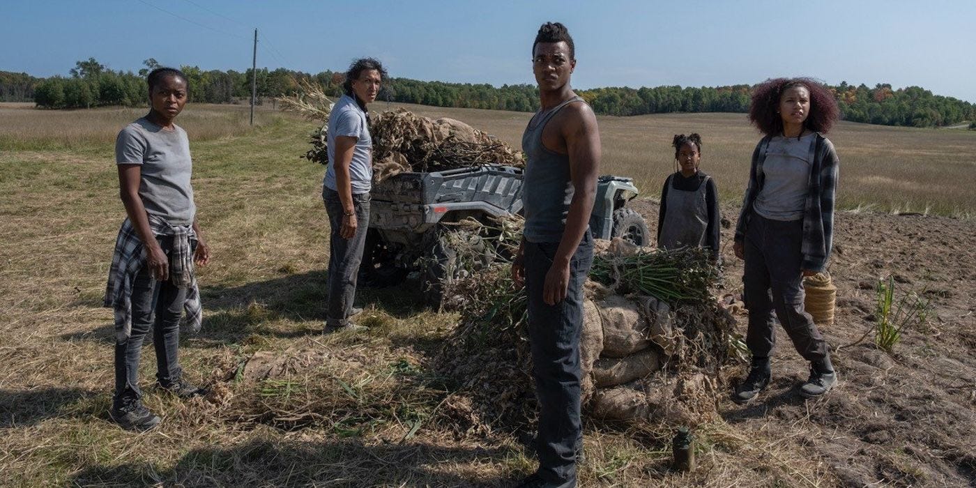 the family in 40 Acres stands around an ATV and some bales on farmland