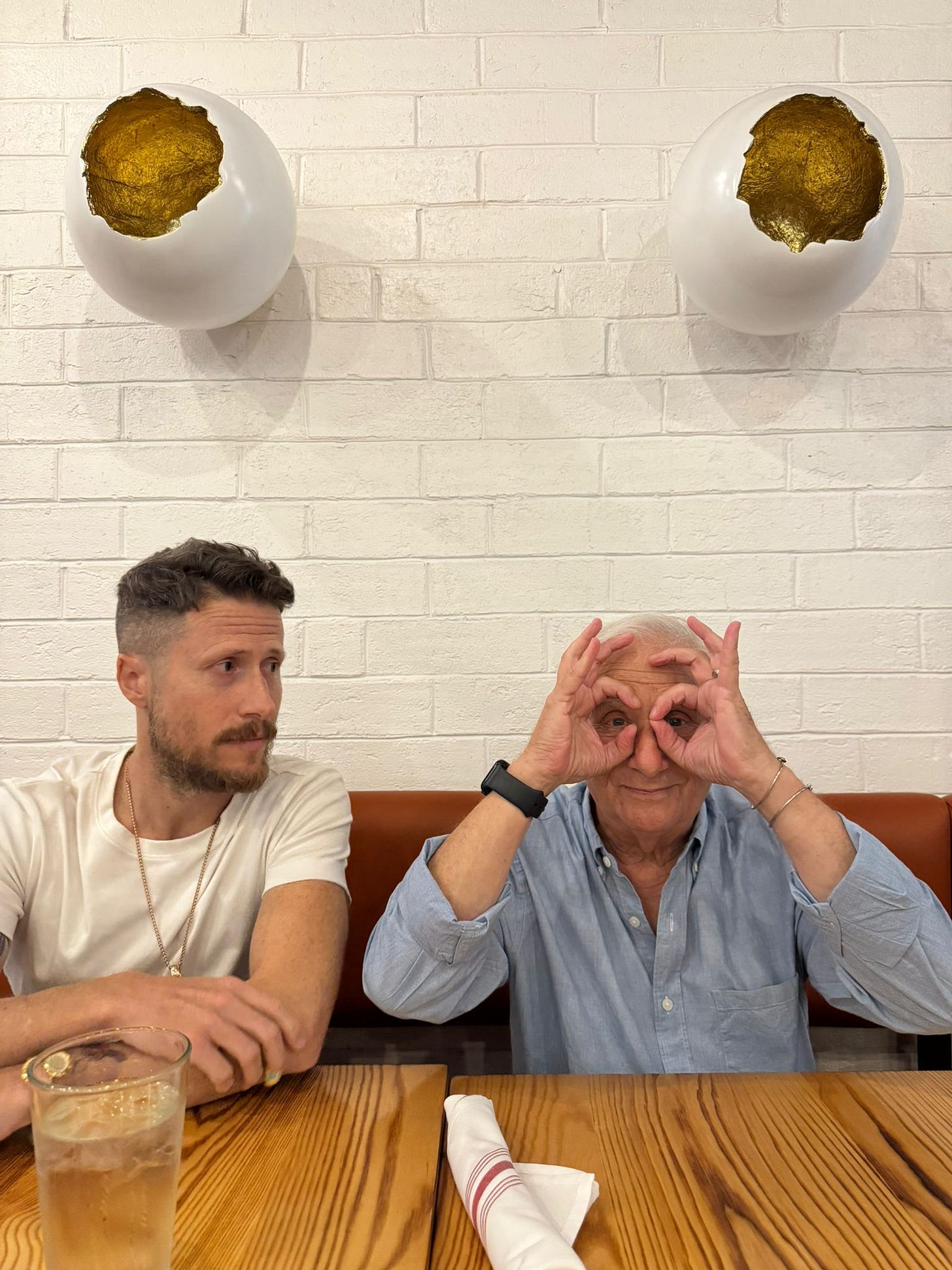 Father and son share a candid, joyful moment at a restaurant—an image reflecting love, family connection, and emotional presence in the face of cancer and caregiving.