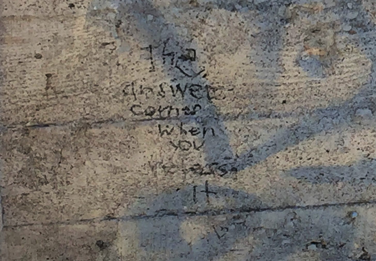 a really shitty photo of words written on concrete. the words say, "The answer comes when you release it"