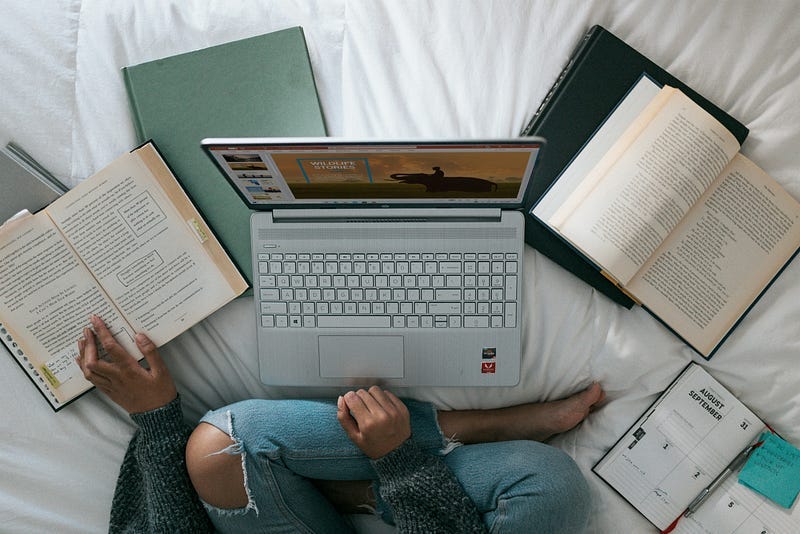 A person studying with a lot of open books and a laptop