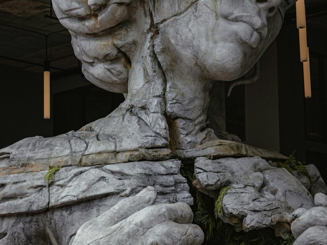 gray concrete statue of man holding stick