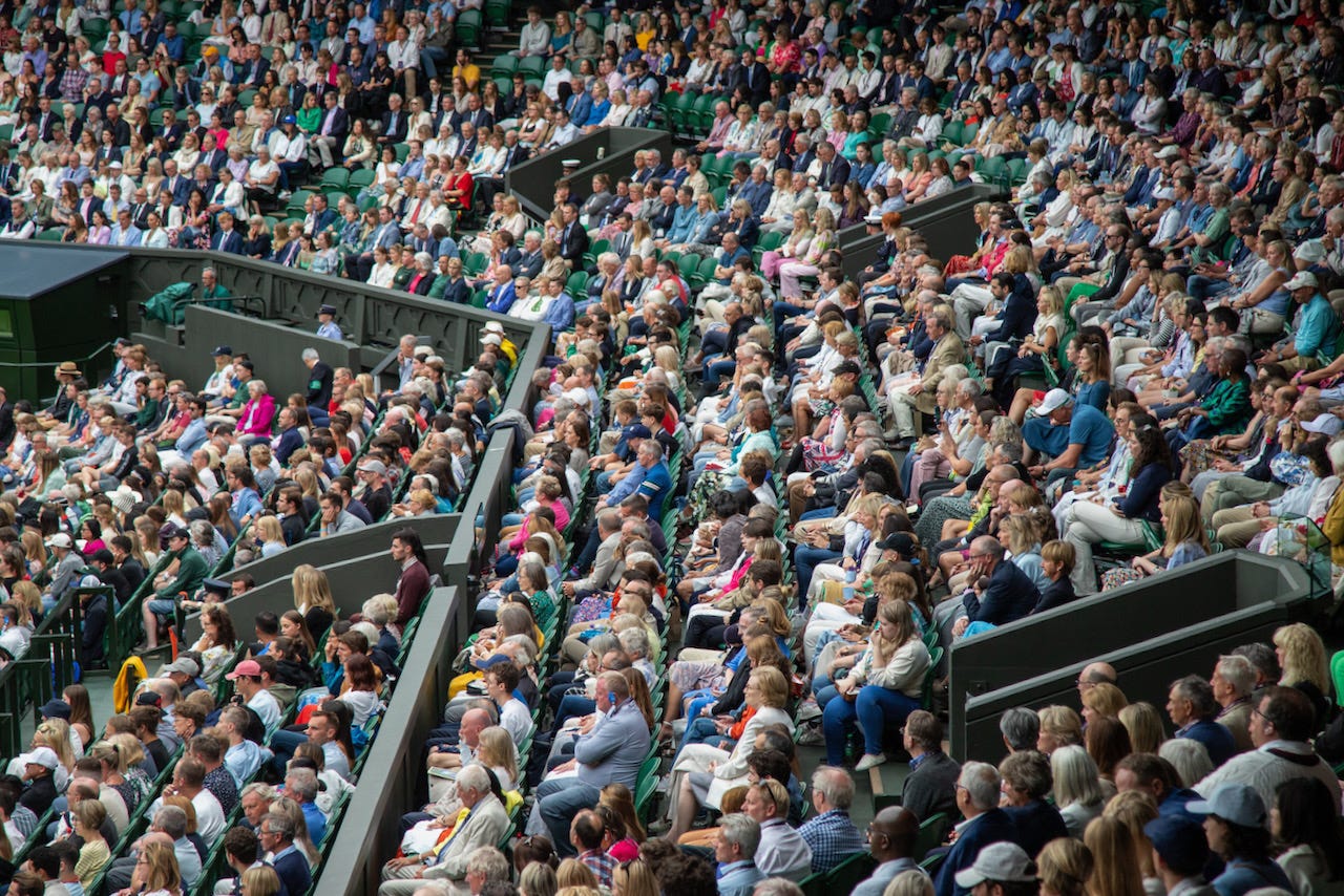 Packed tiers of spectators watching a match on Centre Court at Wimbledon