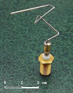 A small metal base supports a metal wire that has many complicated bends in it. A small metal base supports a metal wire that has many complicated bends in it.