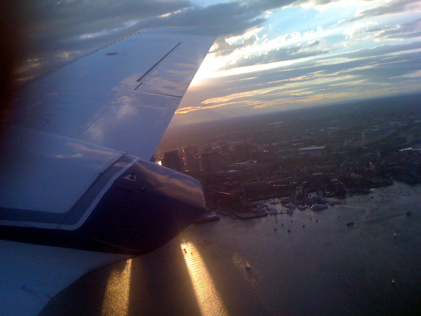 View from a small airplane window at sunset over Boston.
