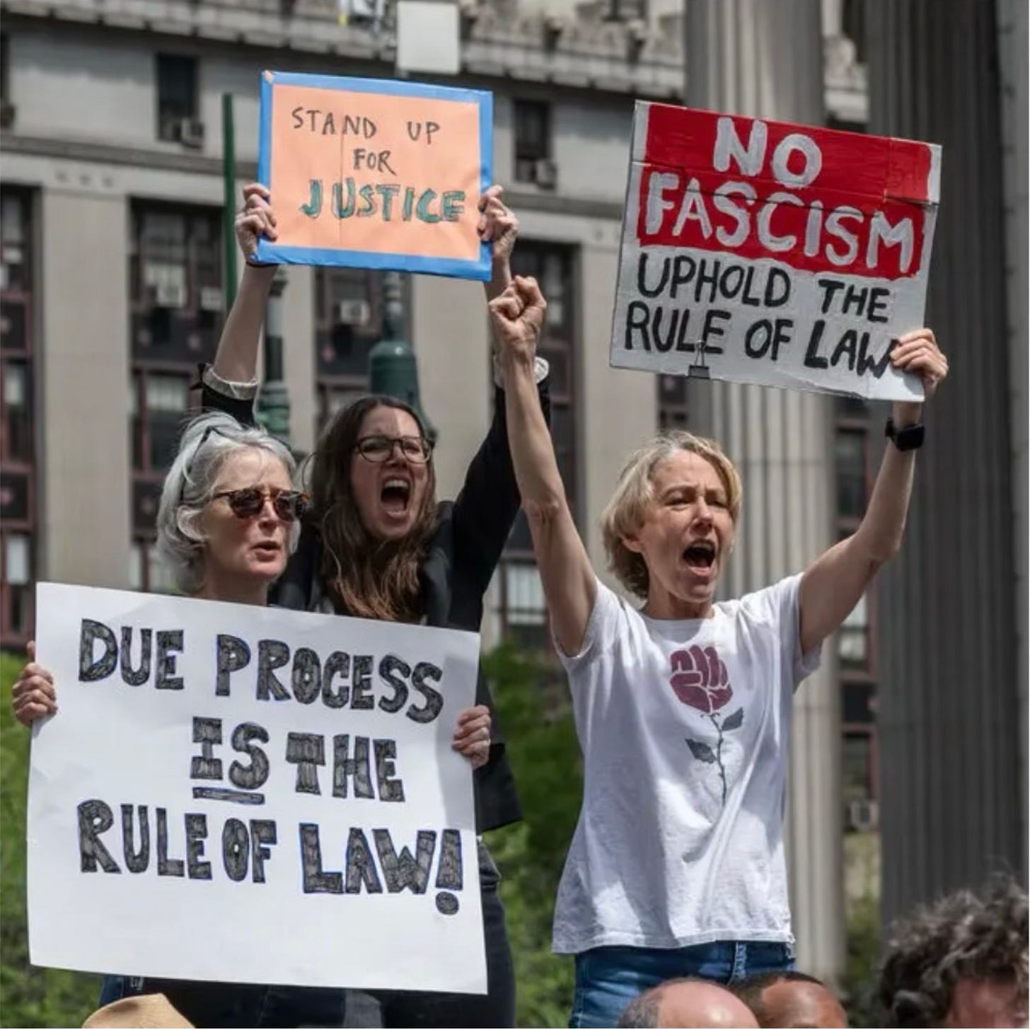 Three women attending a May 3 protest holding up signs calling for due process, rule of law, and justice.