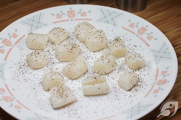 raw sea scallops on a plate with salt and pepper