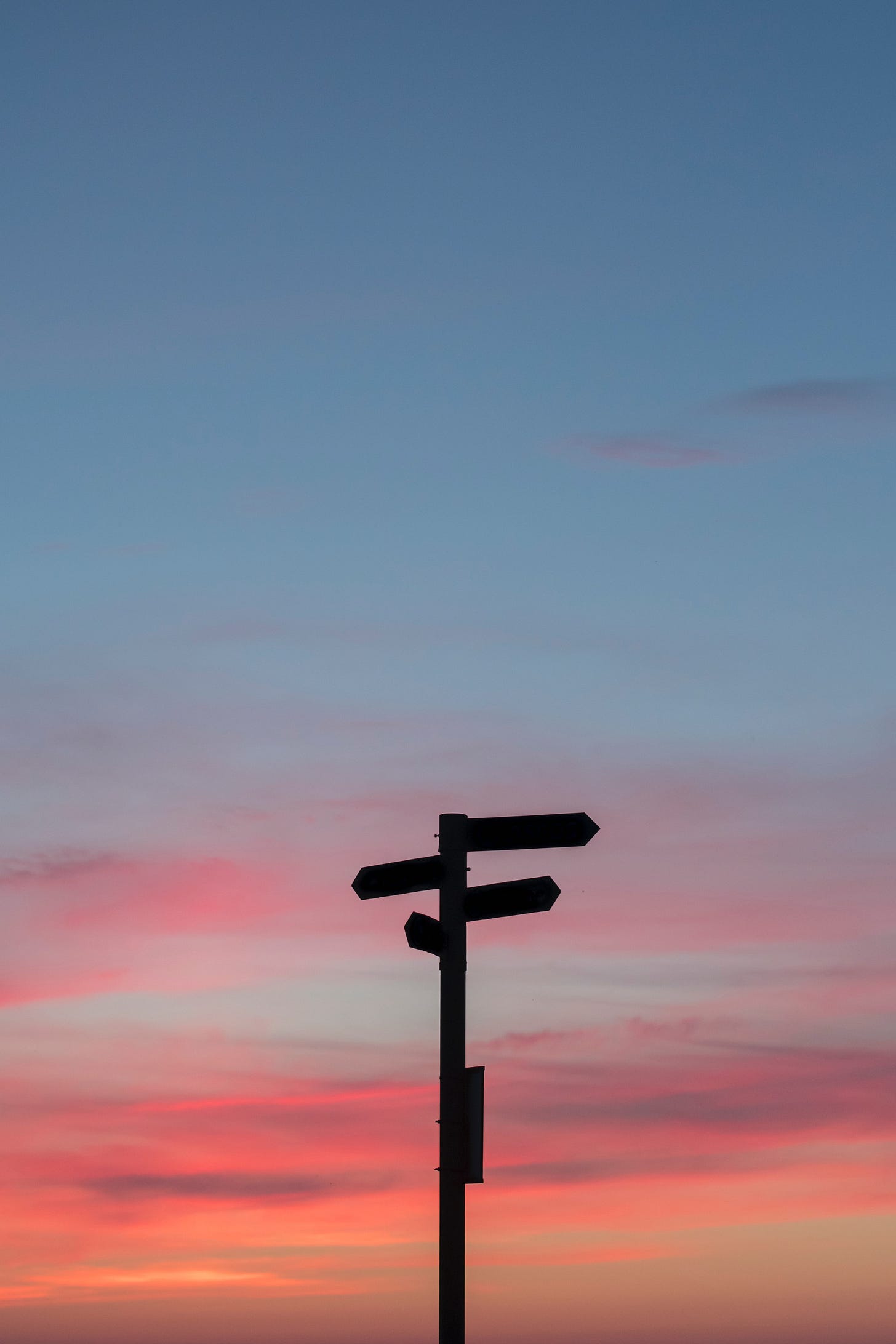 A beautiful pink and blue sky with a sign in silhouette that is pointing many directions. A beautiful pink and blue sky with a sign in silhouette that is pointing many directions.
