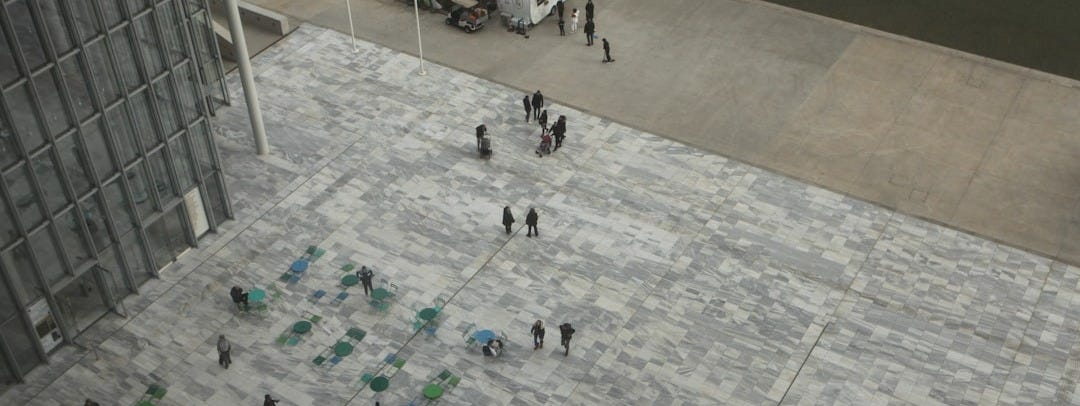 a group of people walking on a sidewalk next to a tall building