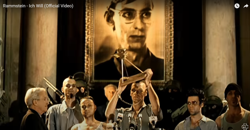 Four prisoners accepting an award with a large sepia photograph of another man behind them.