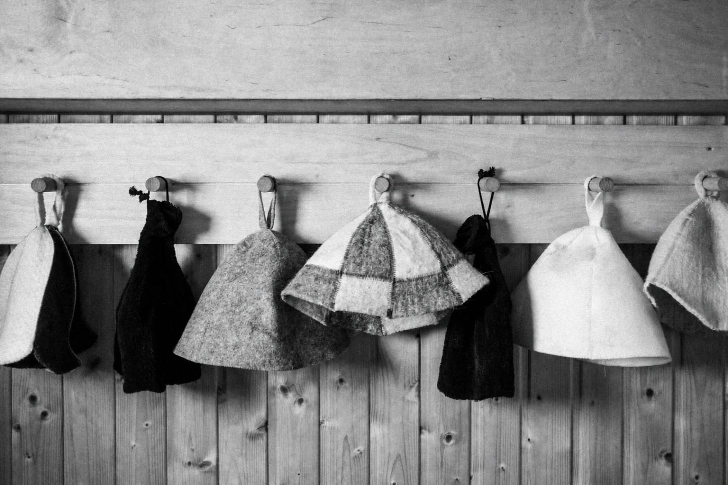 Black-and-white photograph of sauna hats hanging on a wooden wall Black-and-white photograph of sauna hats hanging on a wooden wall
