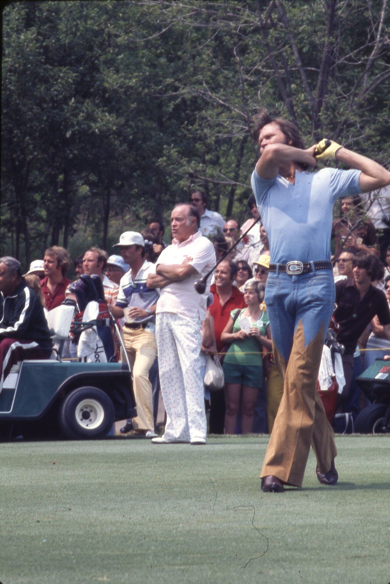 Photo: David E. Lucas / Wikimedia Commons (Public domain) A view of musician Glen Campbell after hitting a tee shot during the 1977 Memorial Tournament pro-am at the Muirfield Village Golf Club. Jackie Gleason sits in a golf cart and Bob Hope stands nearby. Crowds of spectators look on from behind. Campbell