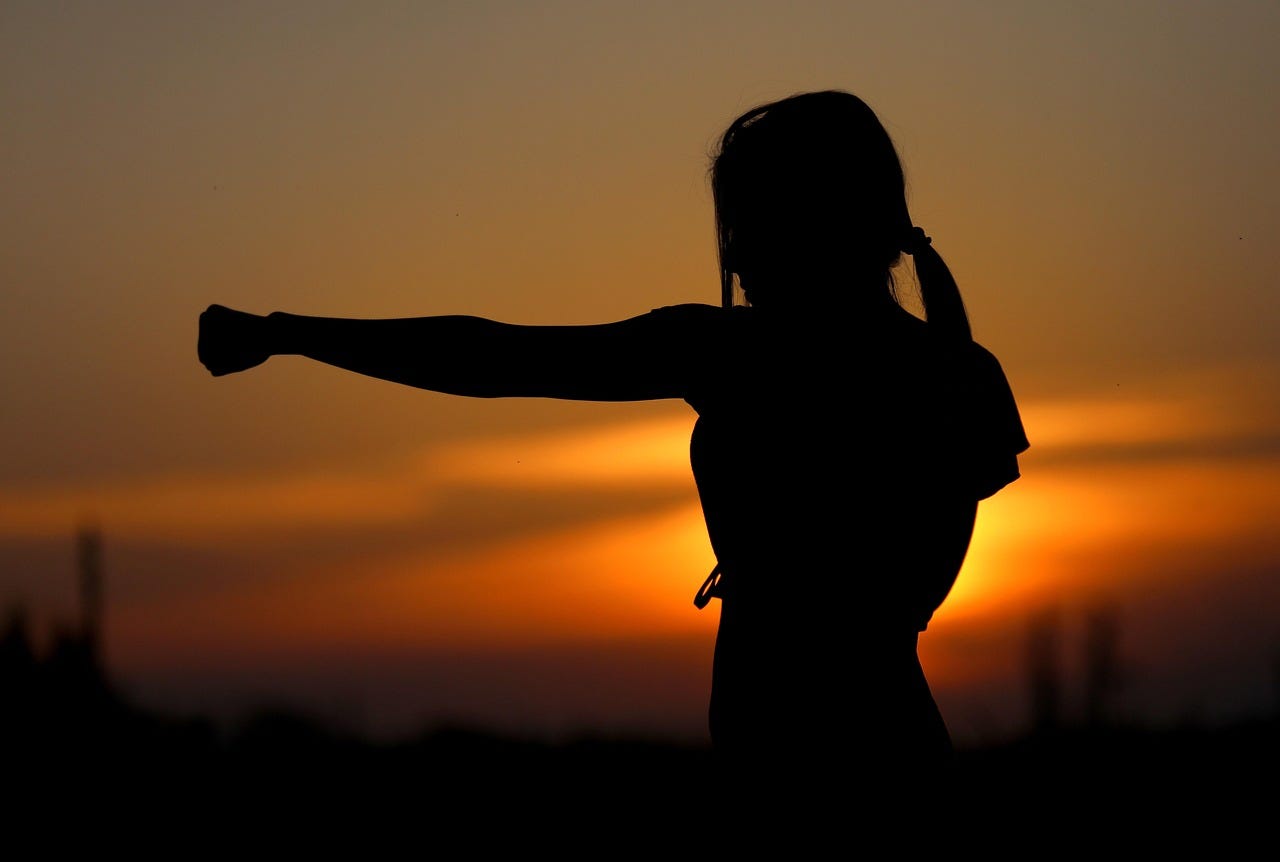A woman punching in a martial arts pose at sunset A woman punching in a martial arts pose at sunset
