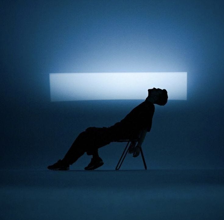 This may contain: a man sitting in a chair with his head down This may contain: a man sitting in a chair with his head down