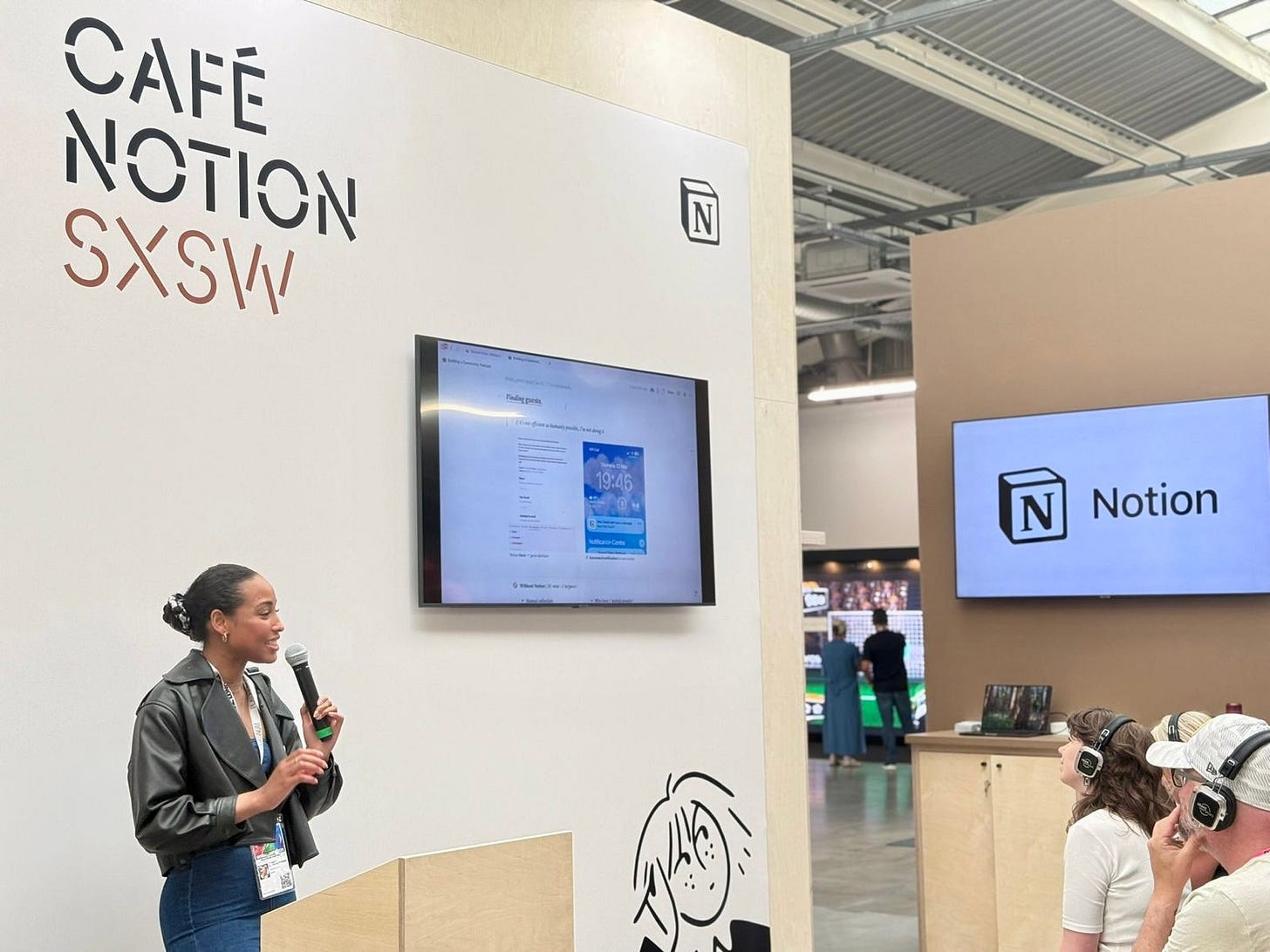 A Black woman speaking with a microphone to an audience at Cafe Notion SXSW, which was a technology and creativity event at SXSW London. A Black woman speaking with a microphone to an audience at Cafe Notion SXSW, which was a technology and creativity event at SXSW London.