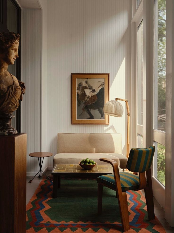 This may contain: a living room filled with furniture and a painting hanging on the wall next to a window