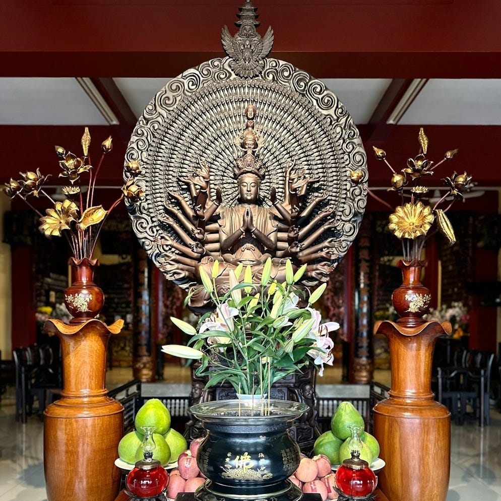 a statue of a buddha surrounded by vases and fruit