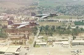 View of the airfield, two military aircraft flying over the city and the surrounding landscape.