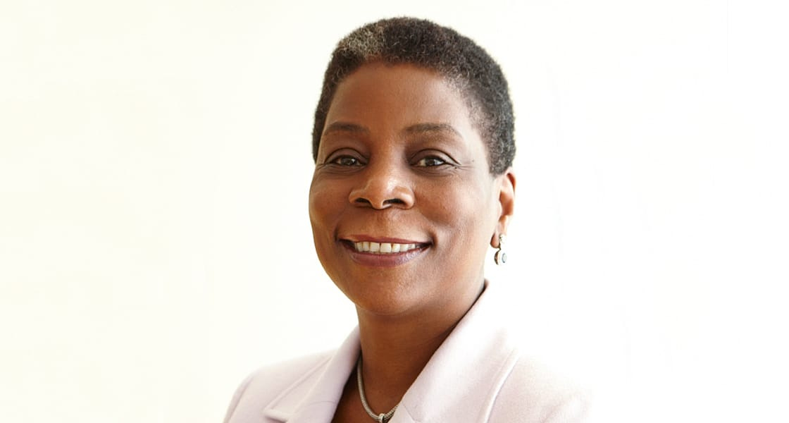 Xerox CEO Ursula Burns faces the camera, smiling, center-frame in a white suit on a white background.