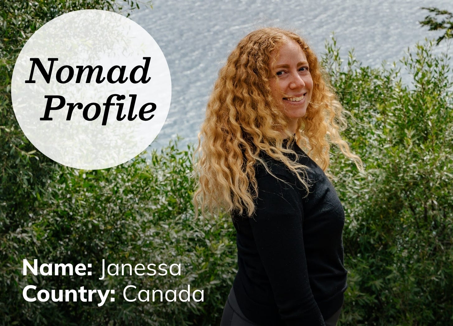 Young white woman with long wavy blond hair standing in front of a lack and trees. 