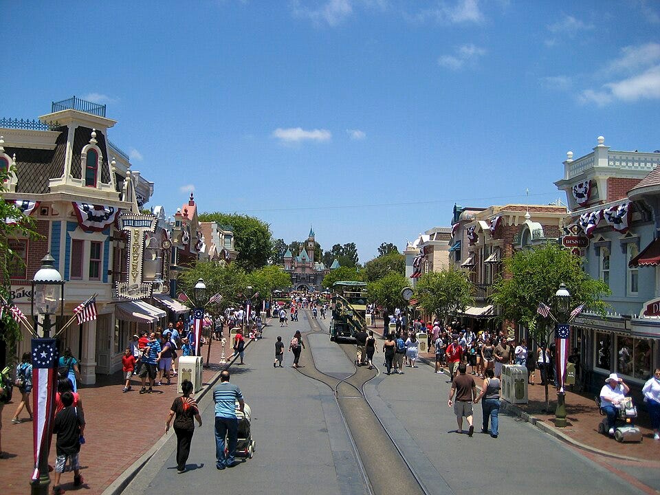 Disneyland Pedestrians gather along the sidewalks and edges of Disneyland's narrow Main Street, U.S.A., framed by continuous building façades on both sides.