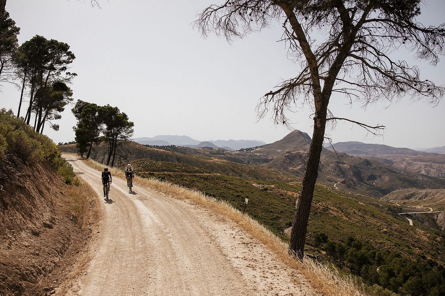 Two riders ride together with the Serra Nevada behind them