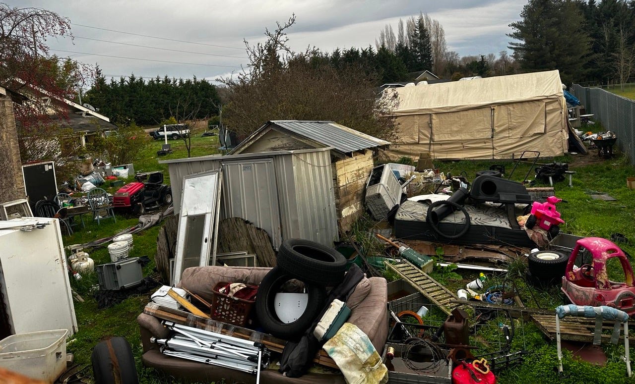 A pile of junk in a yard

Description automatically generated
